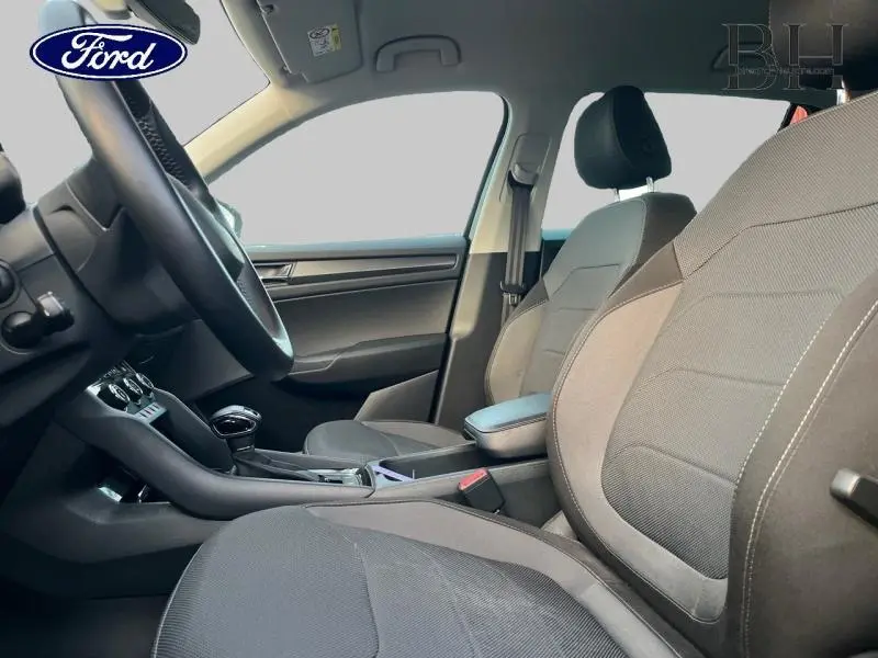 Intérieur avant du Skoda Kodiaq noir, vue côté gauche montrant sièges tissu et console centrale avec accoudoir.