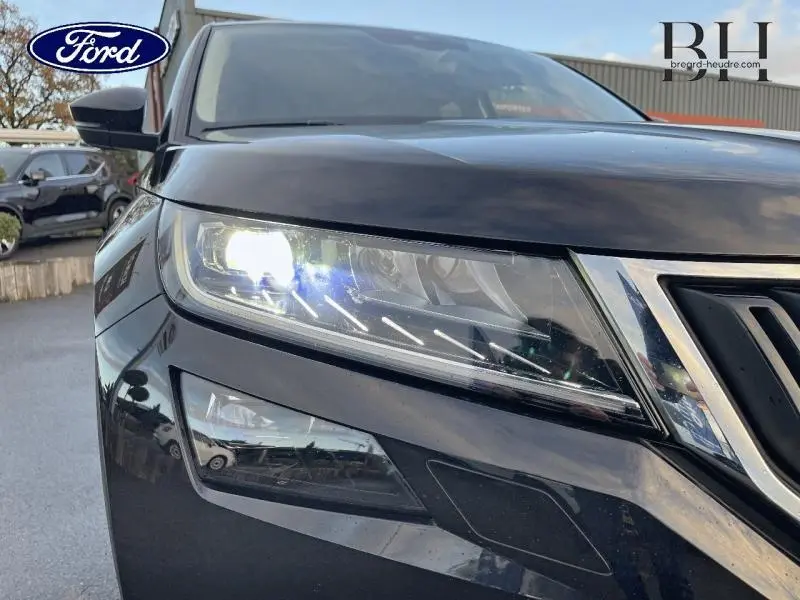Gros plan sur le phare avant droit d'un SKODA KODIAQ noir Magic Nacré avec calandre chromée visible