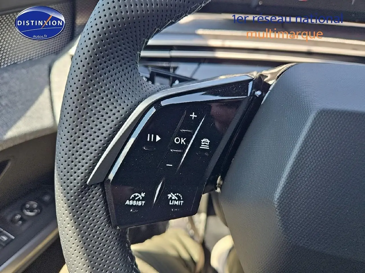 Gros plan sur les commandes du volant en cuir perforé du Peugeot 3008 noir, version hybride 2025, côté gauche.