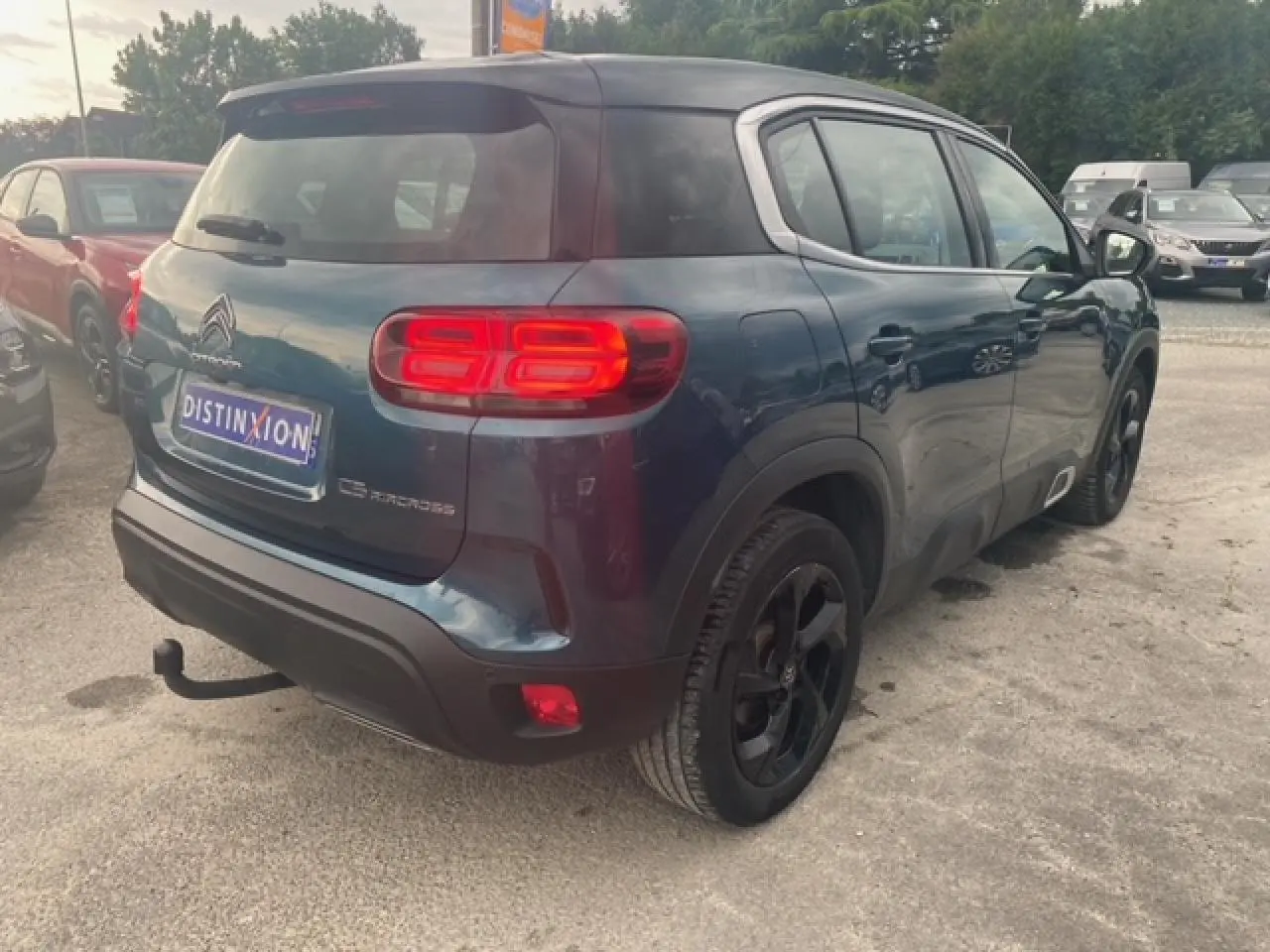 Vue 3/4 arrière droite d'un Citroën C5 Aircross bleu métallisé avec toit noir et attelage col de cygne.