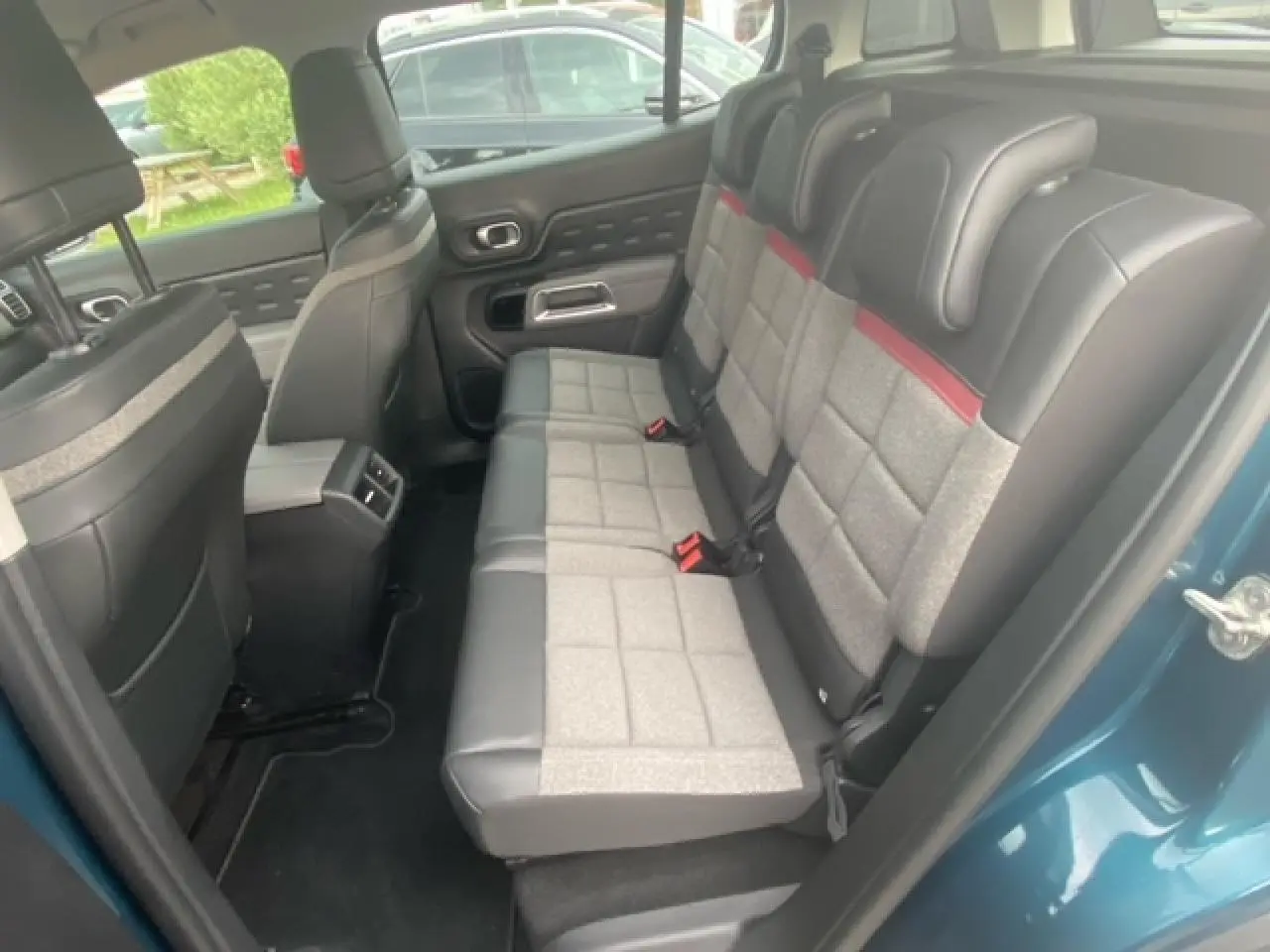 Vue intérieure côté arrière droit du Citroën C5 Aircross bleu toit noir, montrant les sièges arrière bi-matière gris et cuir noir.