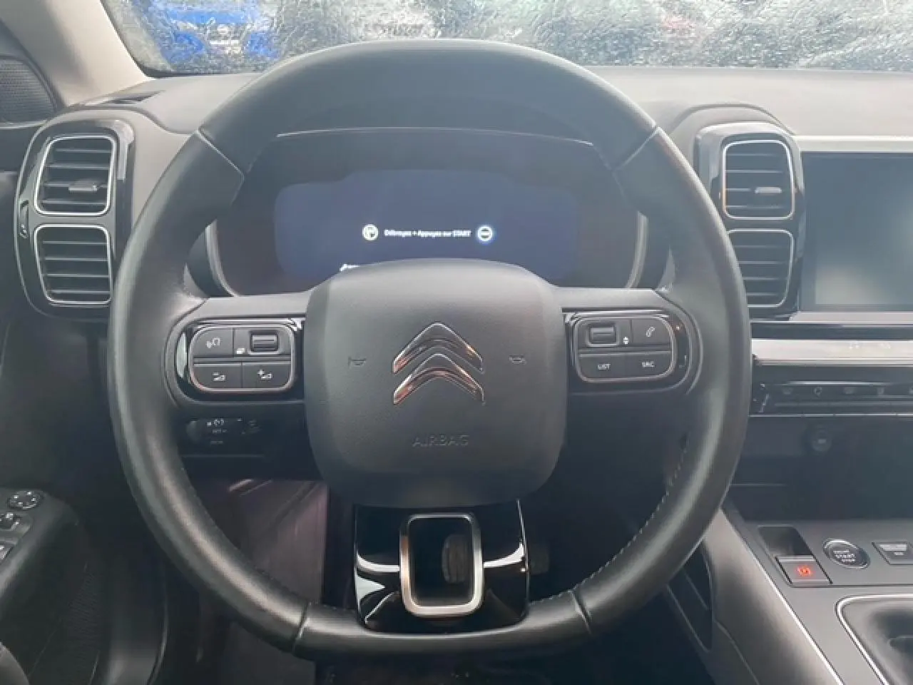 Vue rapprochée du volant cuir noir du Citroën C5 Aircross 2021 avec commandes intégrées et tableau de bord numérique.