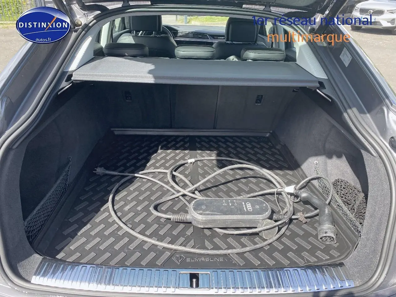 Coffre ouvert d’un Audi Q8 E-TRON gris, vue arrière montrant le câble de recharge électrique dans le compartiment.