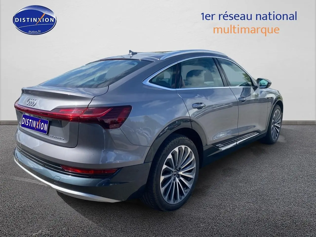 Audi Q8 E-Tron gris en vue 3/4 arrière droit, soulignant ses jantes alu et sa silhouette élancée électrique.