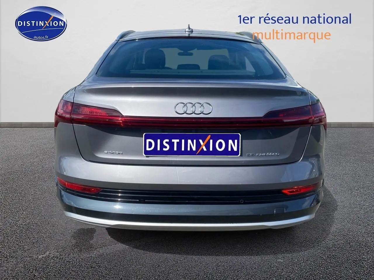 Vue arrière d'un Audi Q8 E-Tron gris 55 quattro 2022 avec feux arrière reliés et logo distinctif au centre.