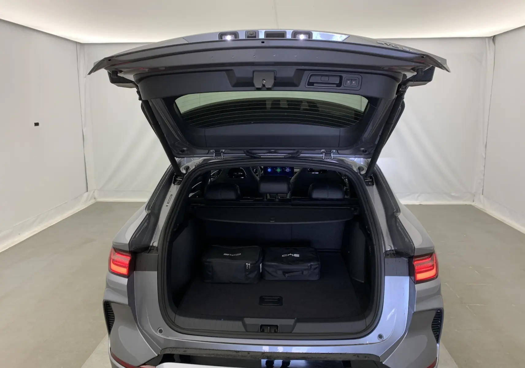 Vue arrière du BYD SEAL U 2026 gris Time Grey Metal avec coffre ouvert et deux sacs noirs à l'intérieur.