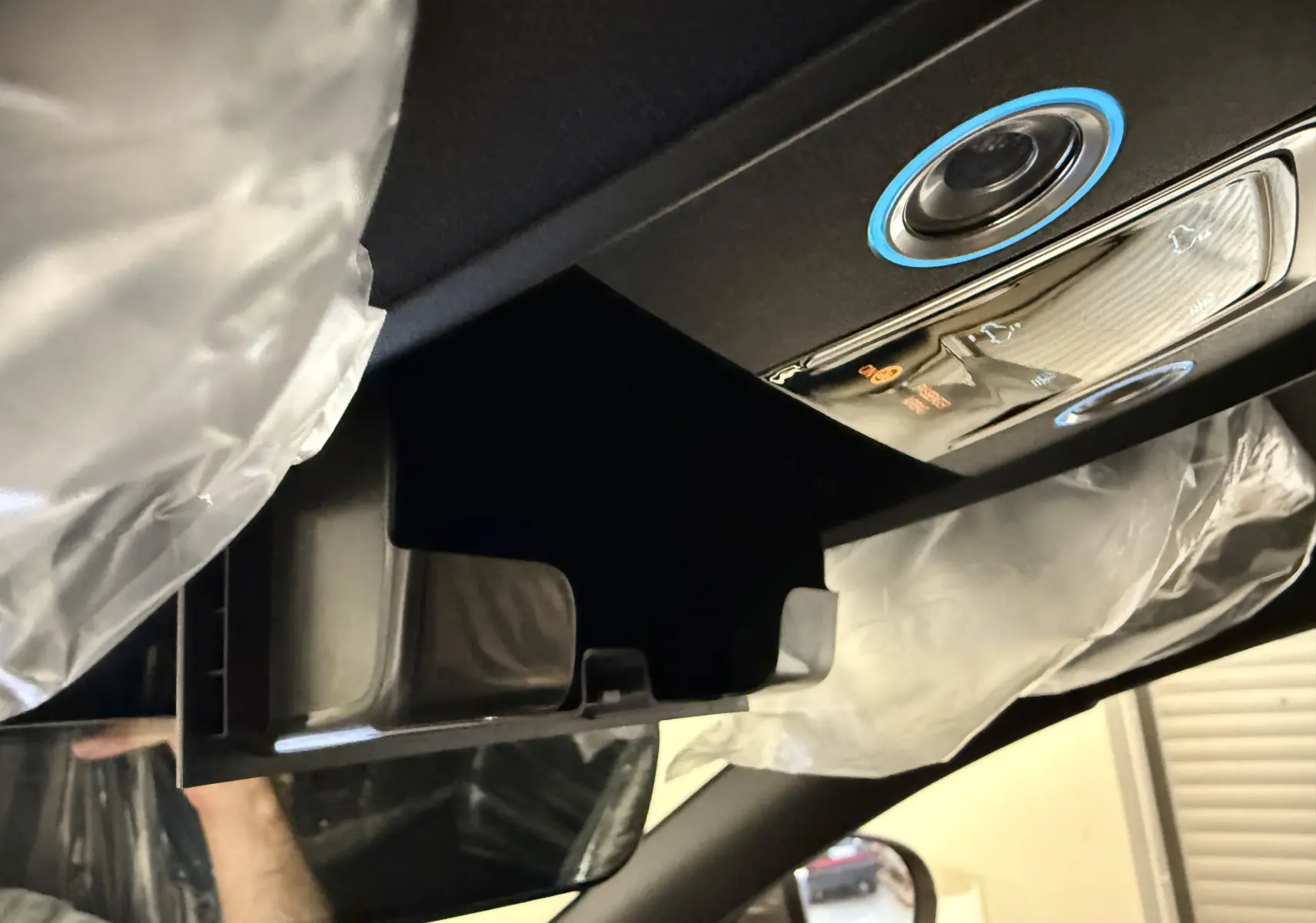 Gros plan sur le rangement ouvert au plafond côté conducteur du BYD SEAL U gris, avec commandes éclairées et airbags visibles.