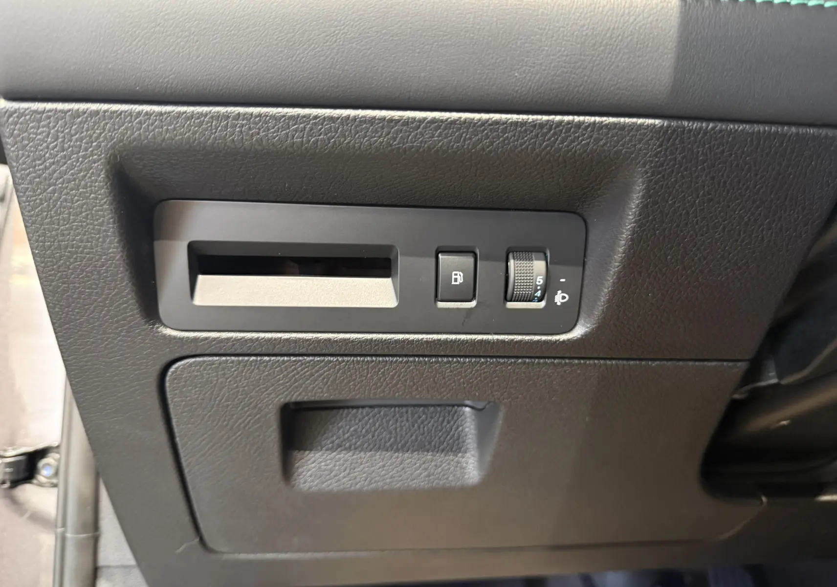 Détail intérieur côté gauche du tableau de bord gris du BYD SEAL U avec commandes d’ouverture et réglage des phares.