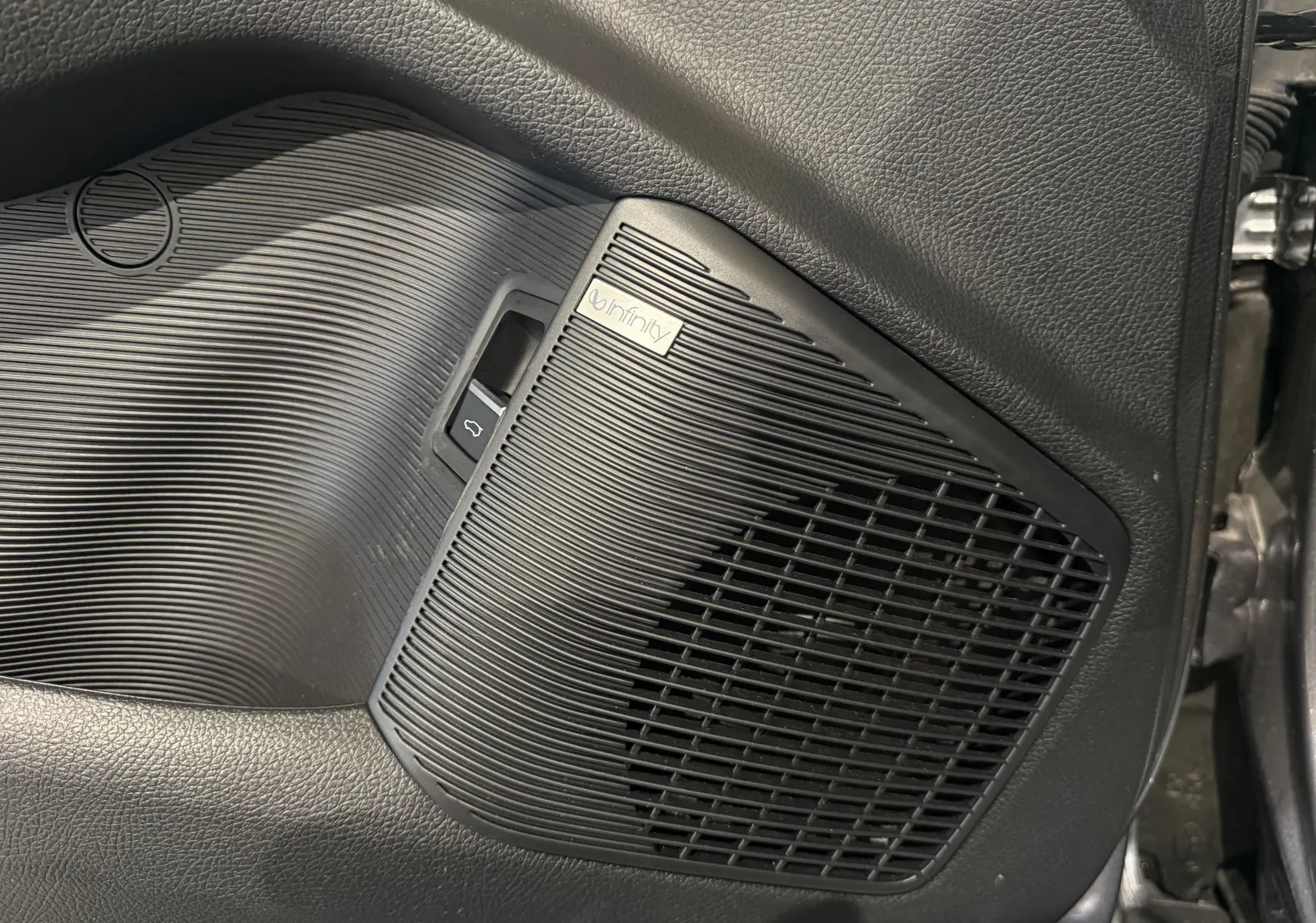 Gros plan sur le haut-parleur Infinity noir intégré à la porte intérieure côté droit du BYD SEAL U gris.