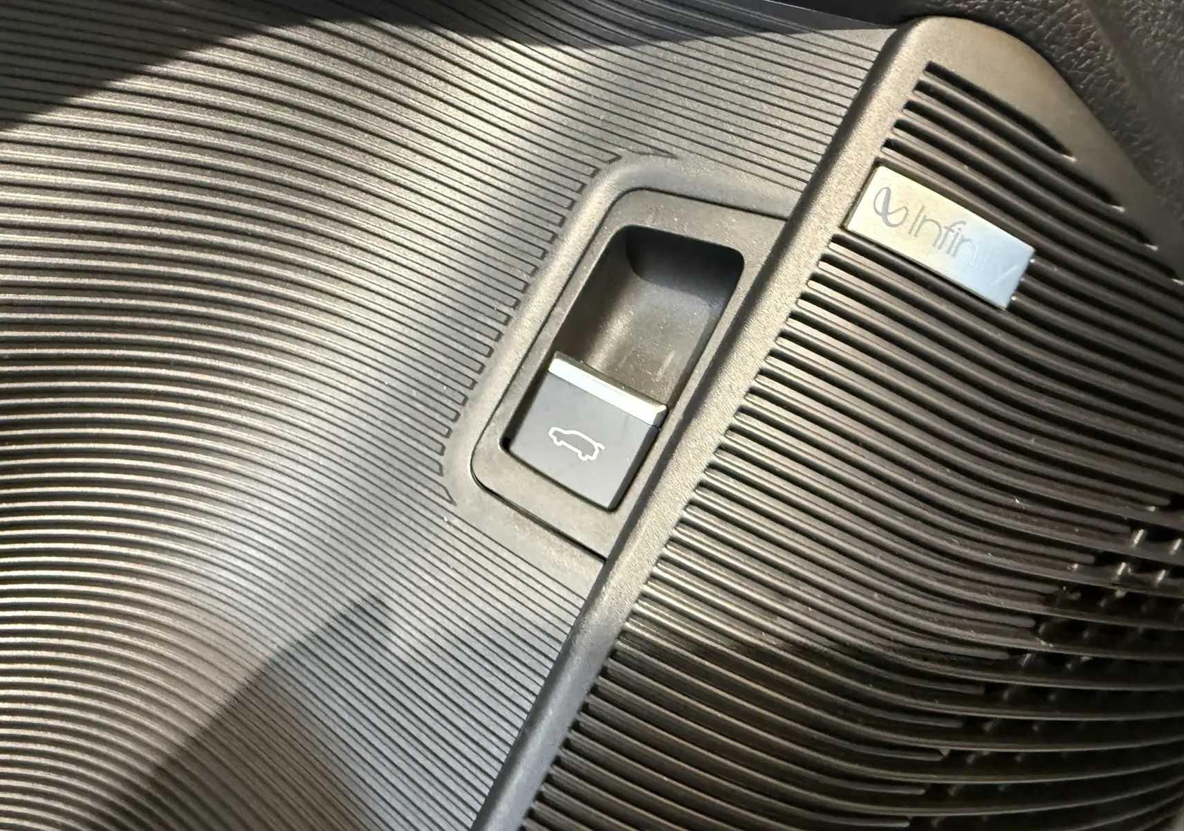 Gros plan sur le bouton d’ouverture de coffre intégré dans la garniture noire texturée de la BYD SEAL U hybride rechargeable.