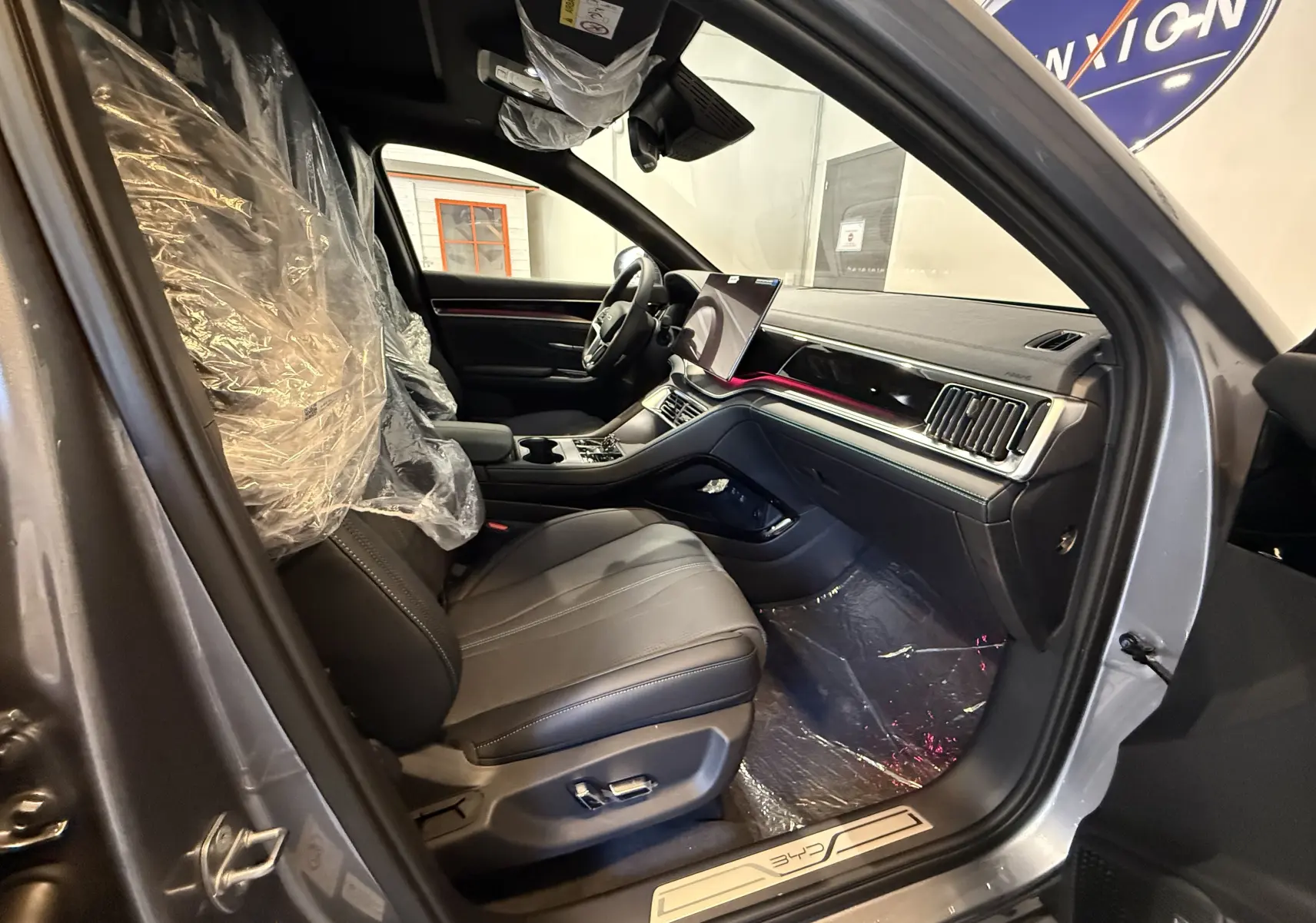 Vue intérieure côté conducteur du BYD SEAL U gris 2026, sièges en cuir noir et tableau de bord moderne avec écran tactile.