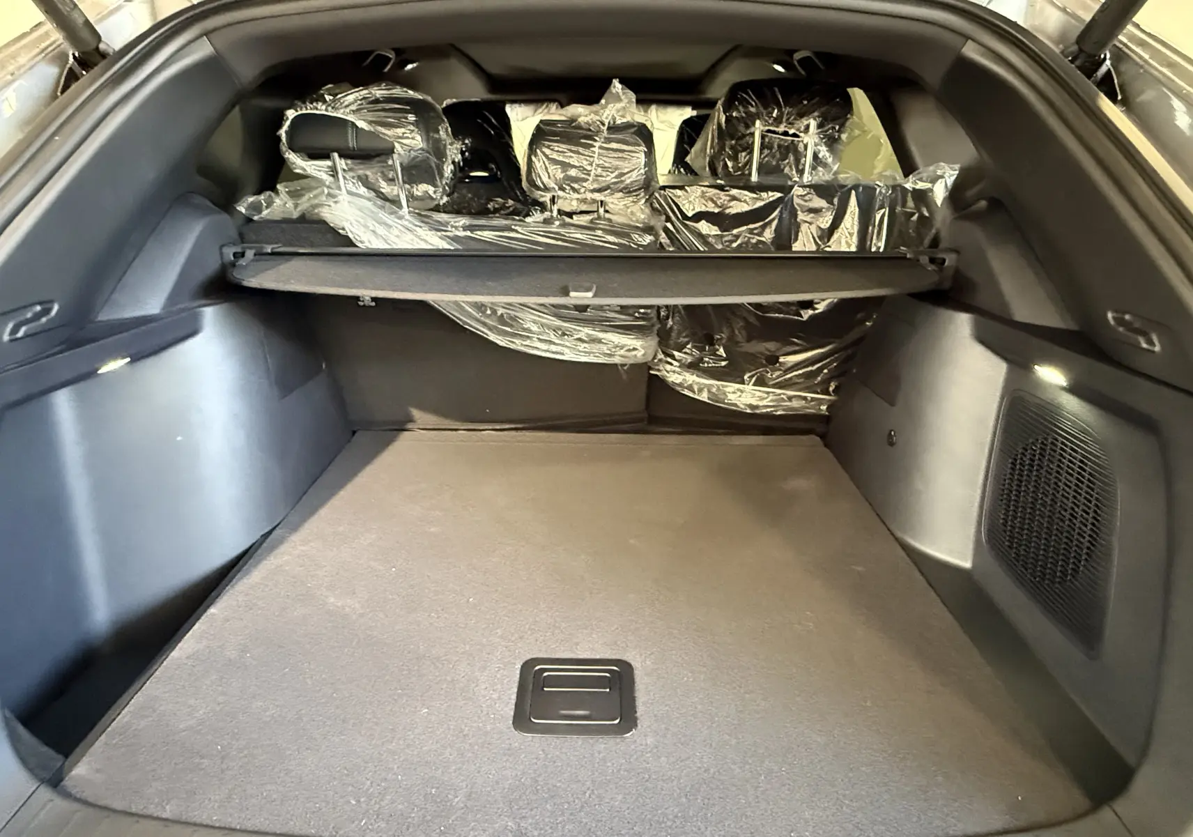 Coffre spacieux du BYD SEAL U gris vu de l'arrière, avec sièges arrière protégés par des housses plastiques.