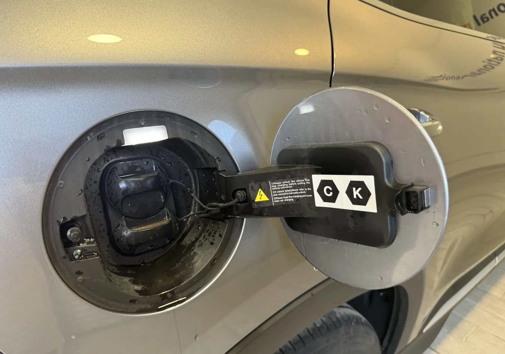 Détail de la trappe de recharge ouverte côté gauche sur BYD SEAL U gris 2026 hybride rechargeable.