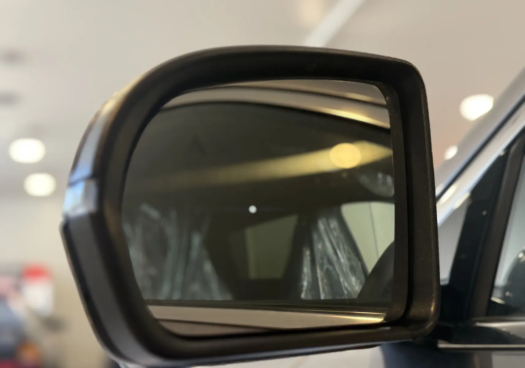 Rétroviseur extérieur côté gauche du BYD SEAL U gris 2026, avec reflet intérieur flou et cadre noir mat.