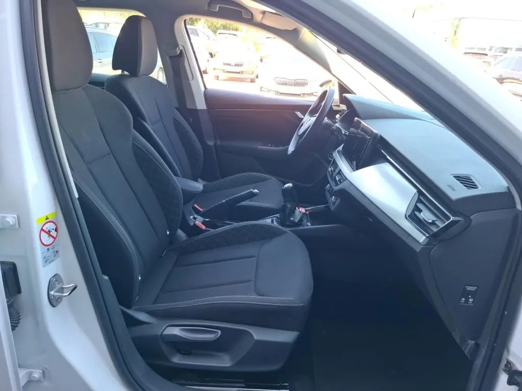 Vue intérieure côté conducteur du Skoda Kamiq blanc 2022, sièges noirs avec console centrale et tableau de bord digital.
