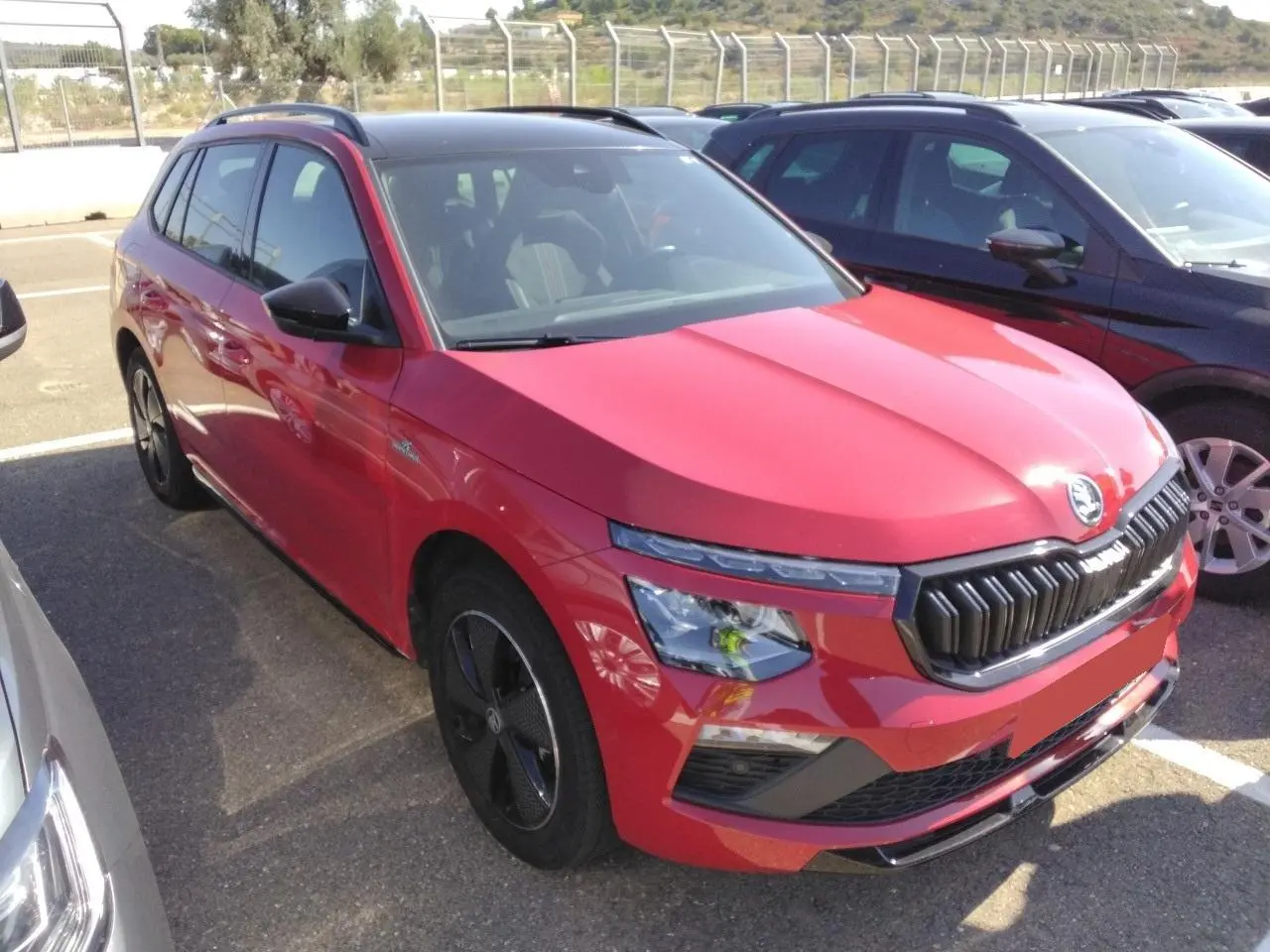 Vue 3/4 avant gauche d’un Skoda Kamiq Monte-Carlo rouge Velvet avec toit panoramique et jantes alliage noires.