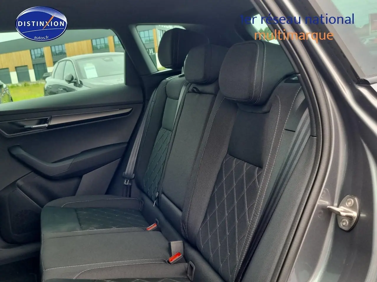 Vue latérale droite de l'intérieur arrière du Skoda Karoq gris graphite avec sièges tissu noir à surpiqûres croisées.