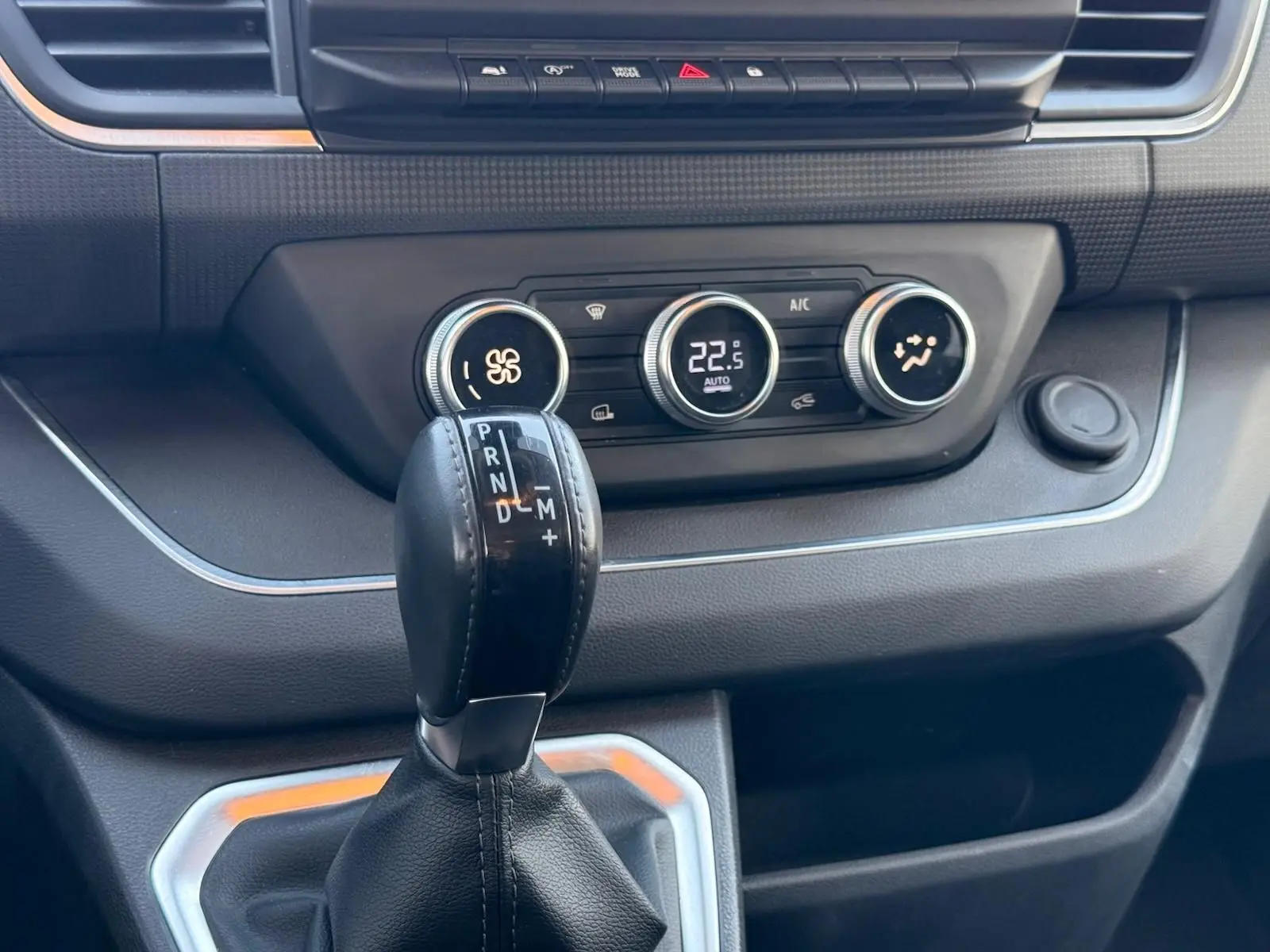 Gros plan sur la console centrale du Renault Trafic gris, avec levier de boîte automatique et commandes de climatisation.