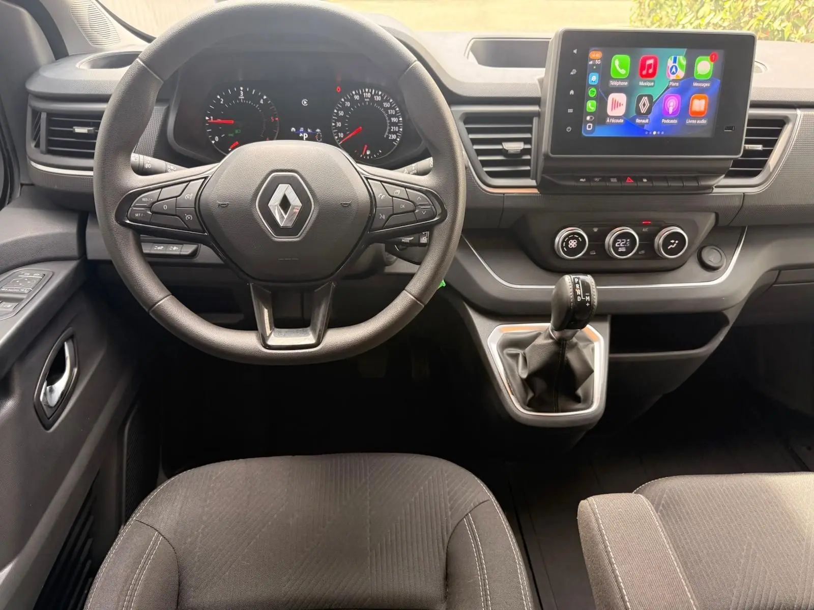 Vue intérieure frontale du tableau de bord gris du Renault Trafic Cabine Approfondie avec volant multifonction et écran tactile central.
