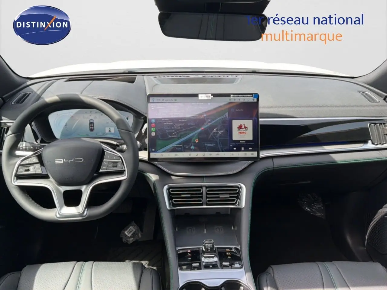 Vue intérieure avant du tableau de bord du BYD SEAL U blanc métal, avec grand écran tactile central et volant multifonction.