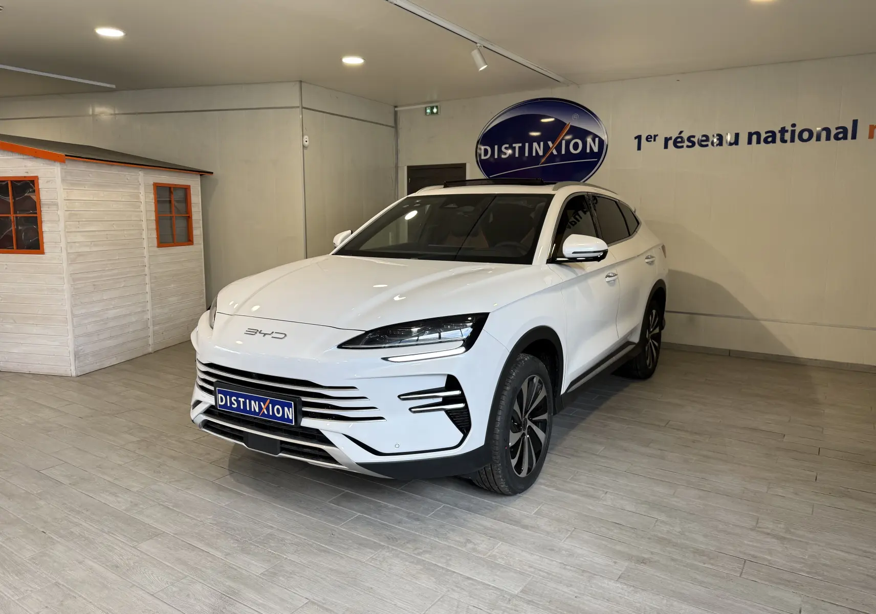 Vue 3/4 avant droite du SUV BYD SEAL U blanc métal, avec calandre moderne et jantes alliage bicolores dans un showroom.