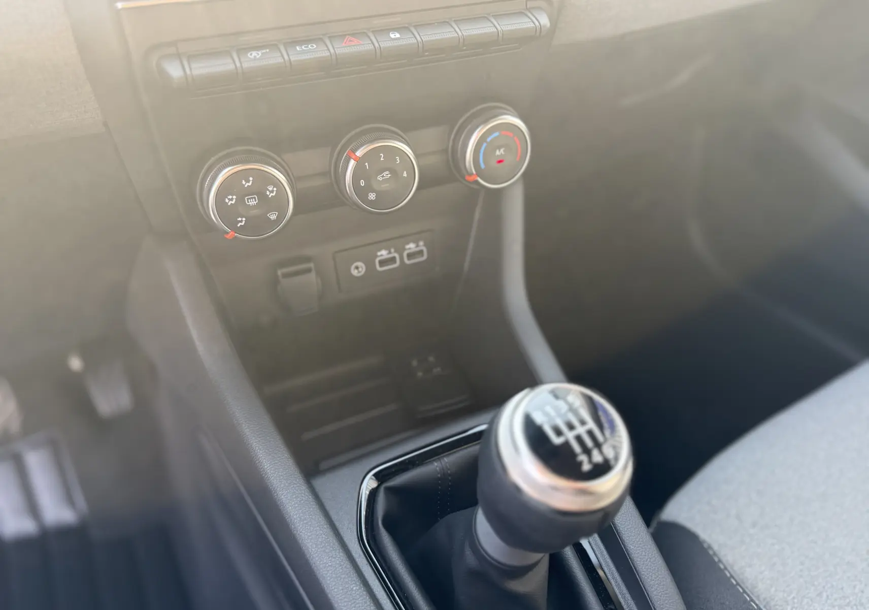 Le levier de vitesses manuel et les commandes de climatisation au centre de la console d'une Renault Clio gris rafale.