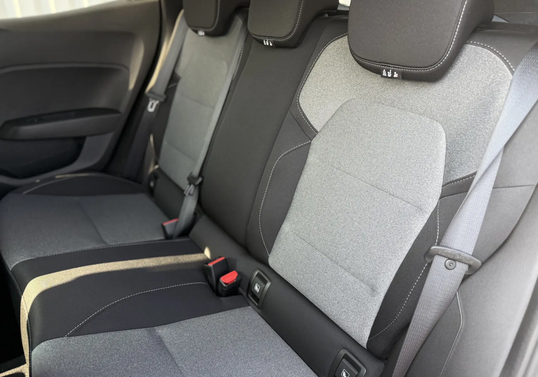 Vue intérieure sur la banquette arrière en tissu bicolore gris clair et foncé de la Renault Clio 2025.