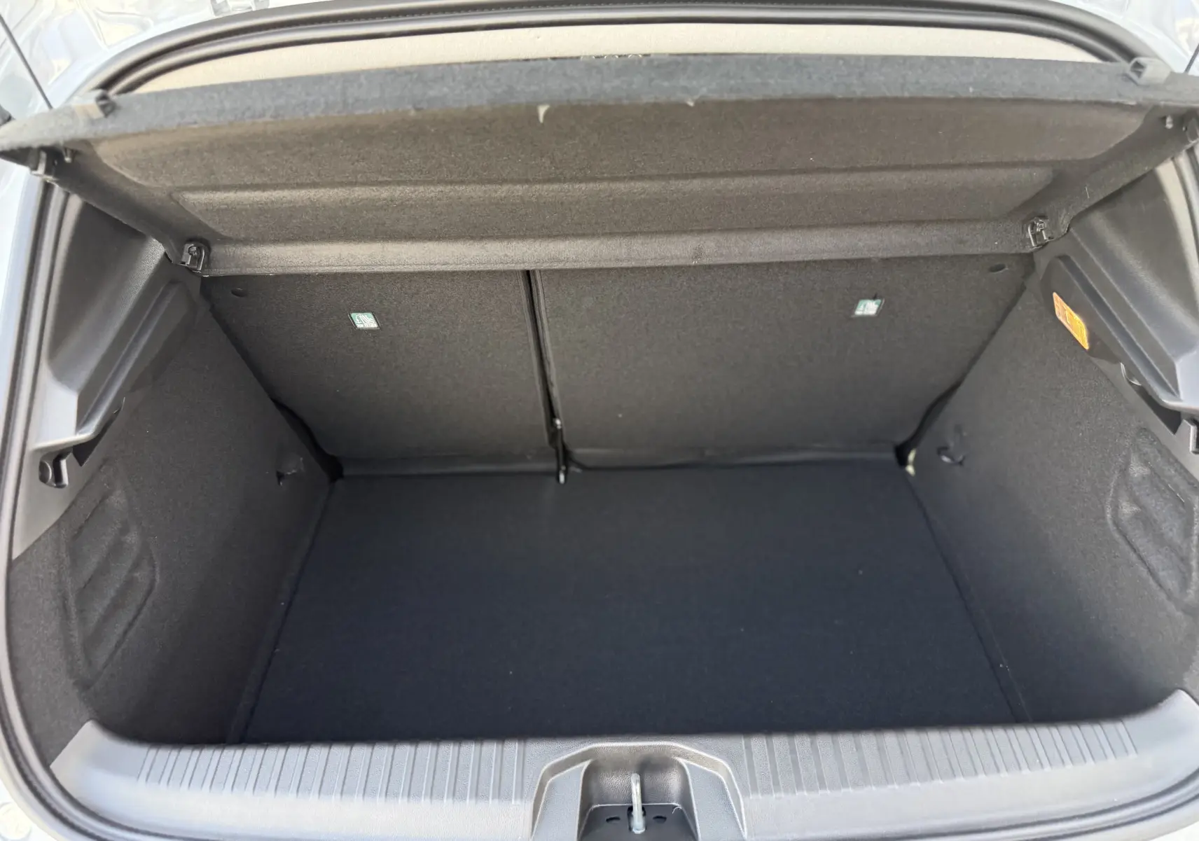 Coffre ouvert d'une Renault Clio 1.5 dCi gris Rafale métal, montrant un espace de rangement propre et spacieux.