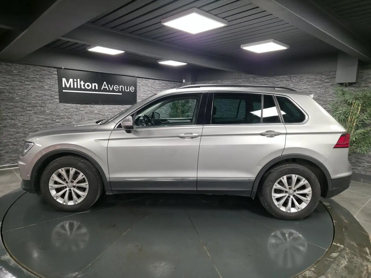 Vue latérale droite d'un Volkswagen Tiguan gris métallisé 2018 en intérieur avec jantes alliage 17 pouces.