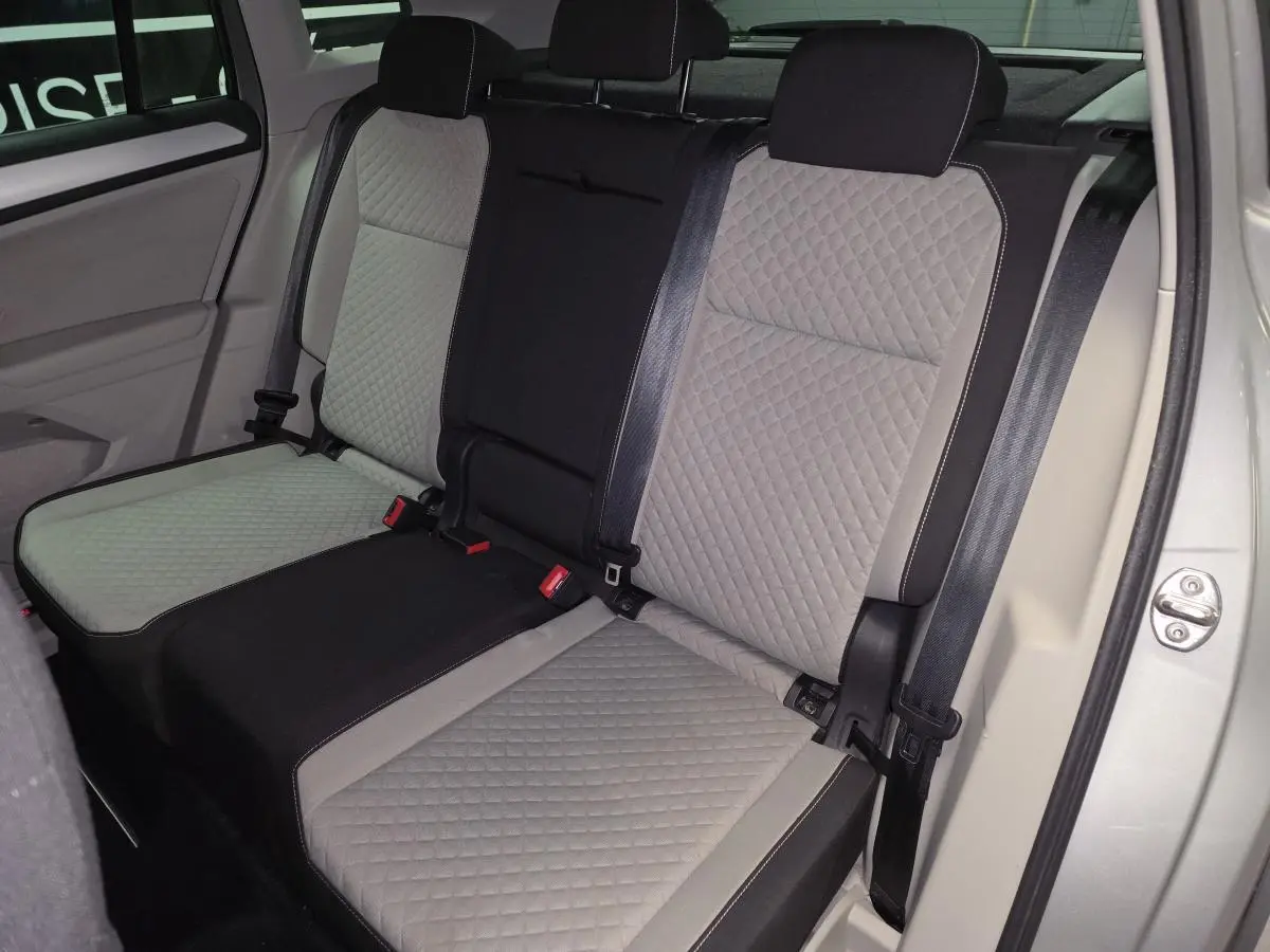 Vue intérieure sur les sièges arrière gris à motif losange du Volkswagen Tiguan 2018, avec ceintures de sécurité visibles.