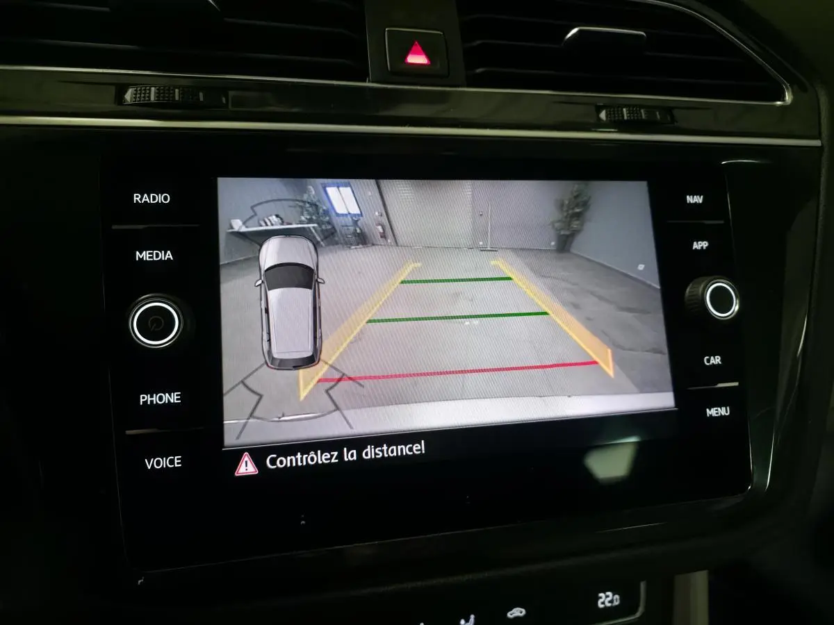 Écran de caméra de recul du Volkswagen Tiguan gris, affichant les lignes d’aide au stationnement en intérieur.