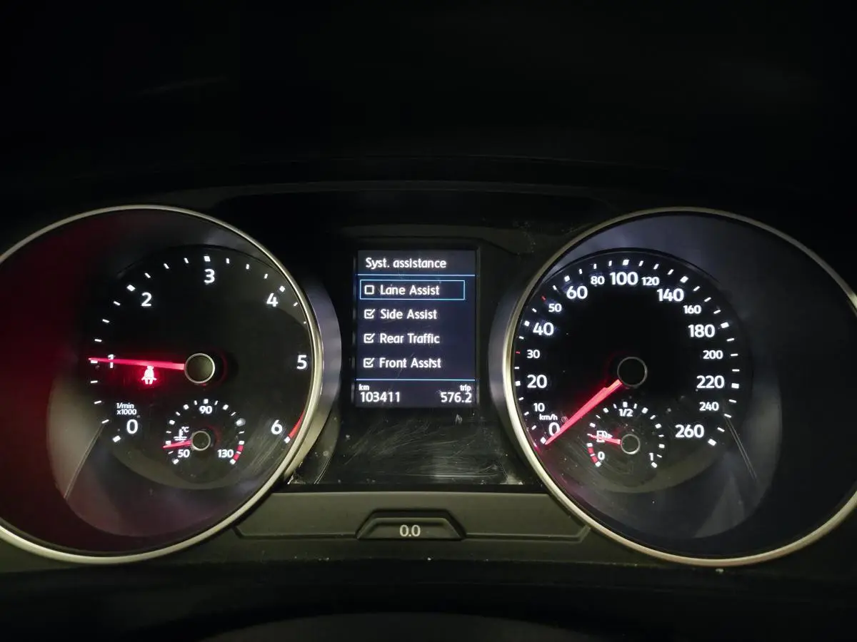 Vue rapprochée du tableau de bord du Volkswagen Tiguan gris, affichant les compteurs et les aides à la conduite activées.