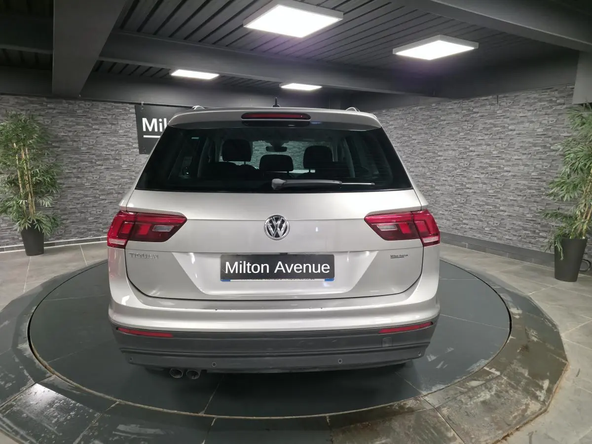 Vue arrière d'un Volkswagen Tiguan gris métallisé 2018 dans un showroom avec éclairage intérieur.