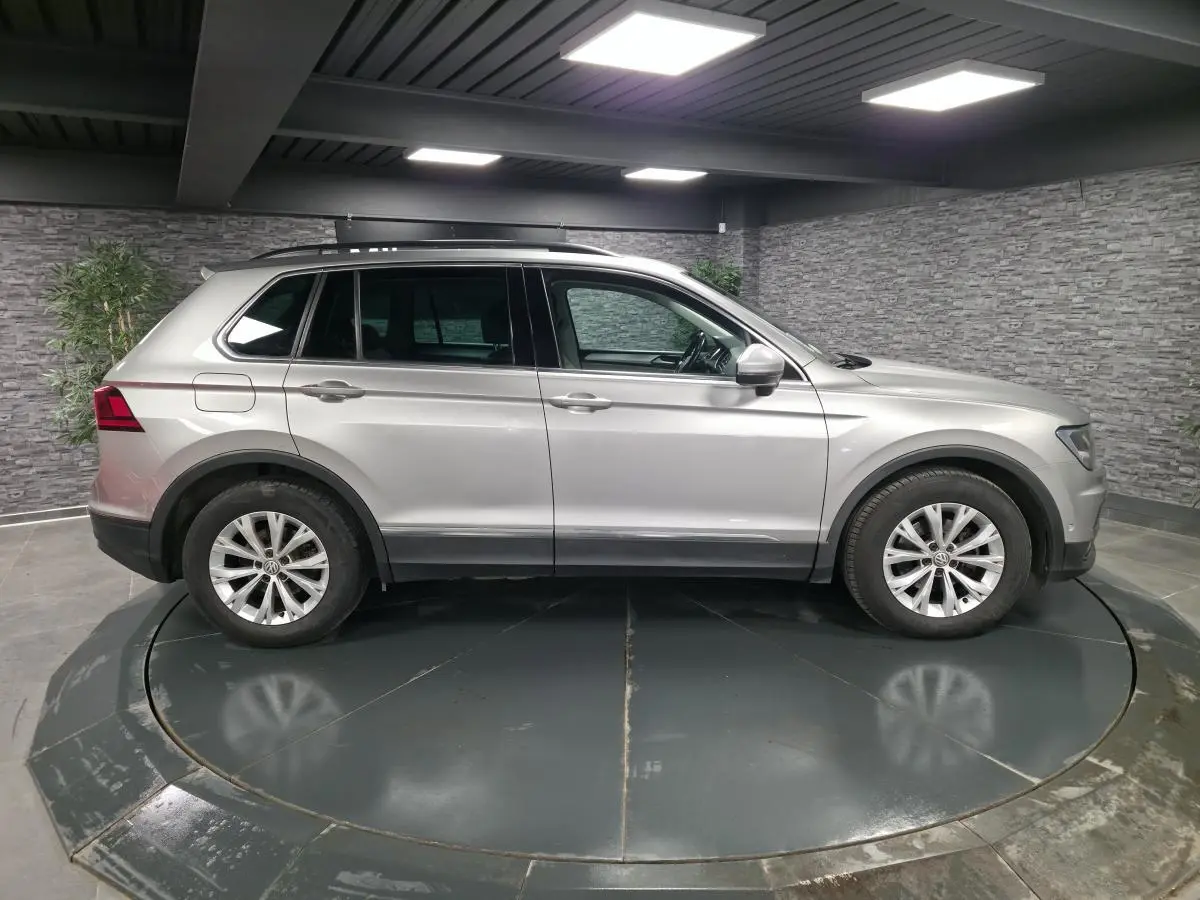 Vue latérale droite d'un Volkswagen Tiguan gris métallisé 2018 sur plateau tournant en intérieur.