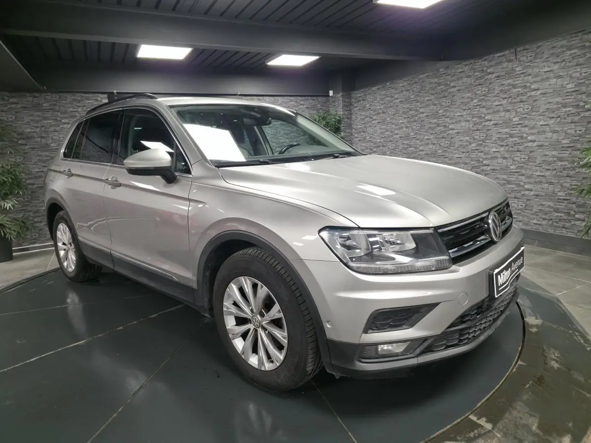 Volkswagen Tiguan gris métallisé en 3/4 avant droit, avec jantes alliage et calandre noire brillante.