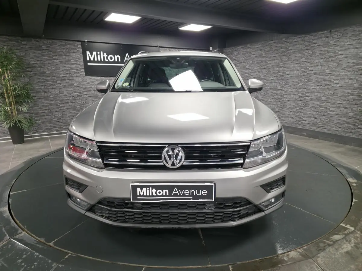 Vue avant d'un Volkswagen Tiguan gris métallisé 2018 avec calandre noire et phares halogènes, en showroom.