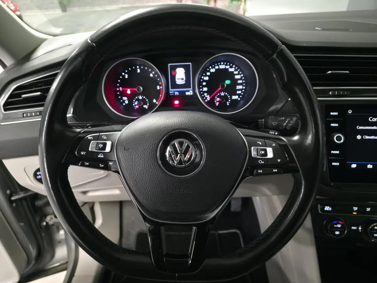 Vue rapprochée du volant cuir multifonctions noir et du tableau de bord éclairé d’un Volkswagen Tiguan gris.