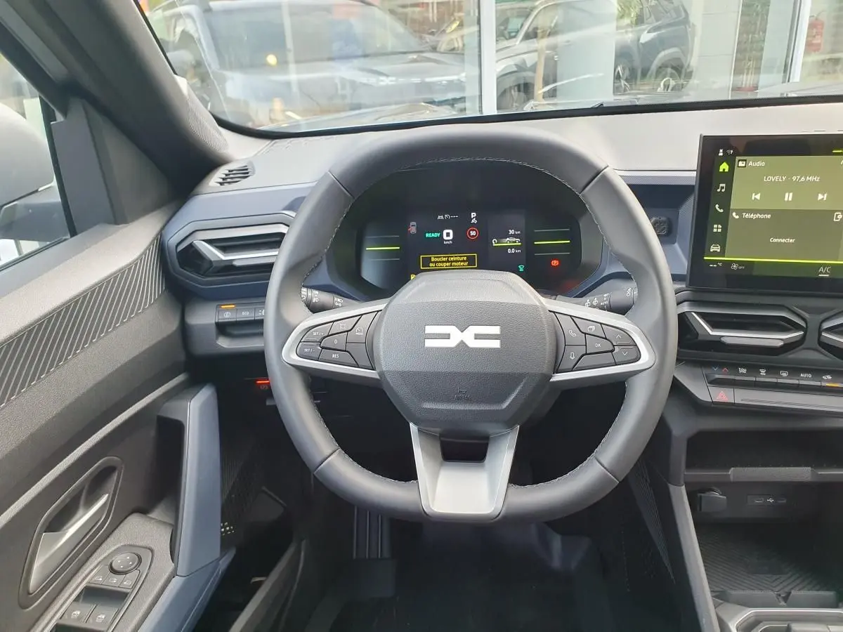 Vue intérieure centrée sur le volant multifonction et le tableau de bord numérique du Dacia Duster 2026.