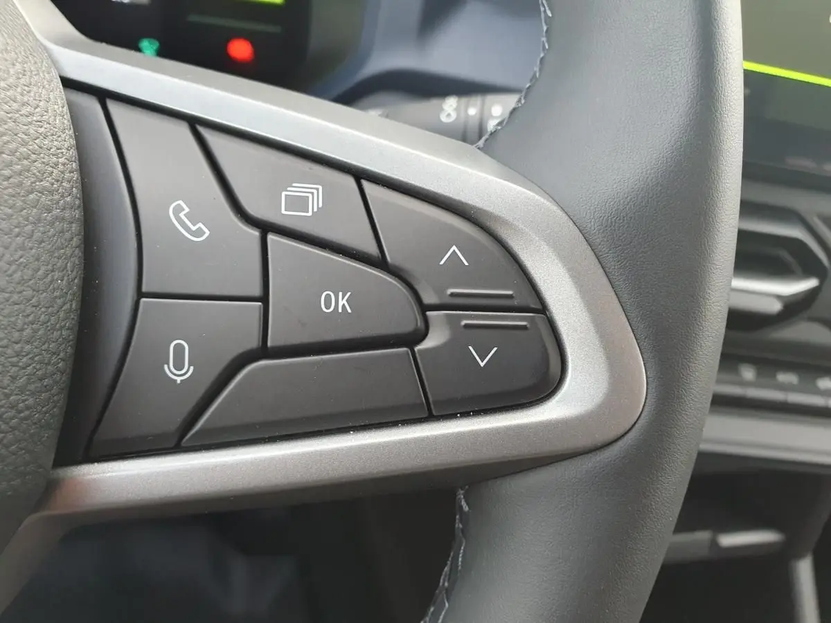 Gros plan sur les commandes multifonctions à droite du volant du Dacia Duster 1.6 Hybrid 140 gris schiste, intérieur moderne.