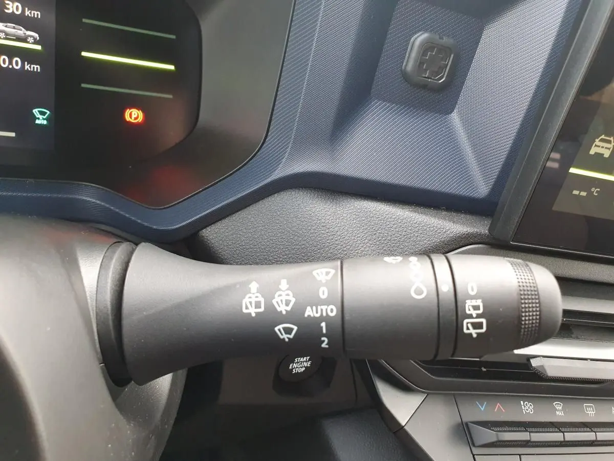 Gros plan sur la manette d’essuie-glace côté gauche du tableau de bord du Dacia Duster gris schiste 2026.