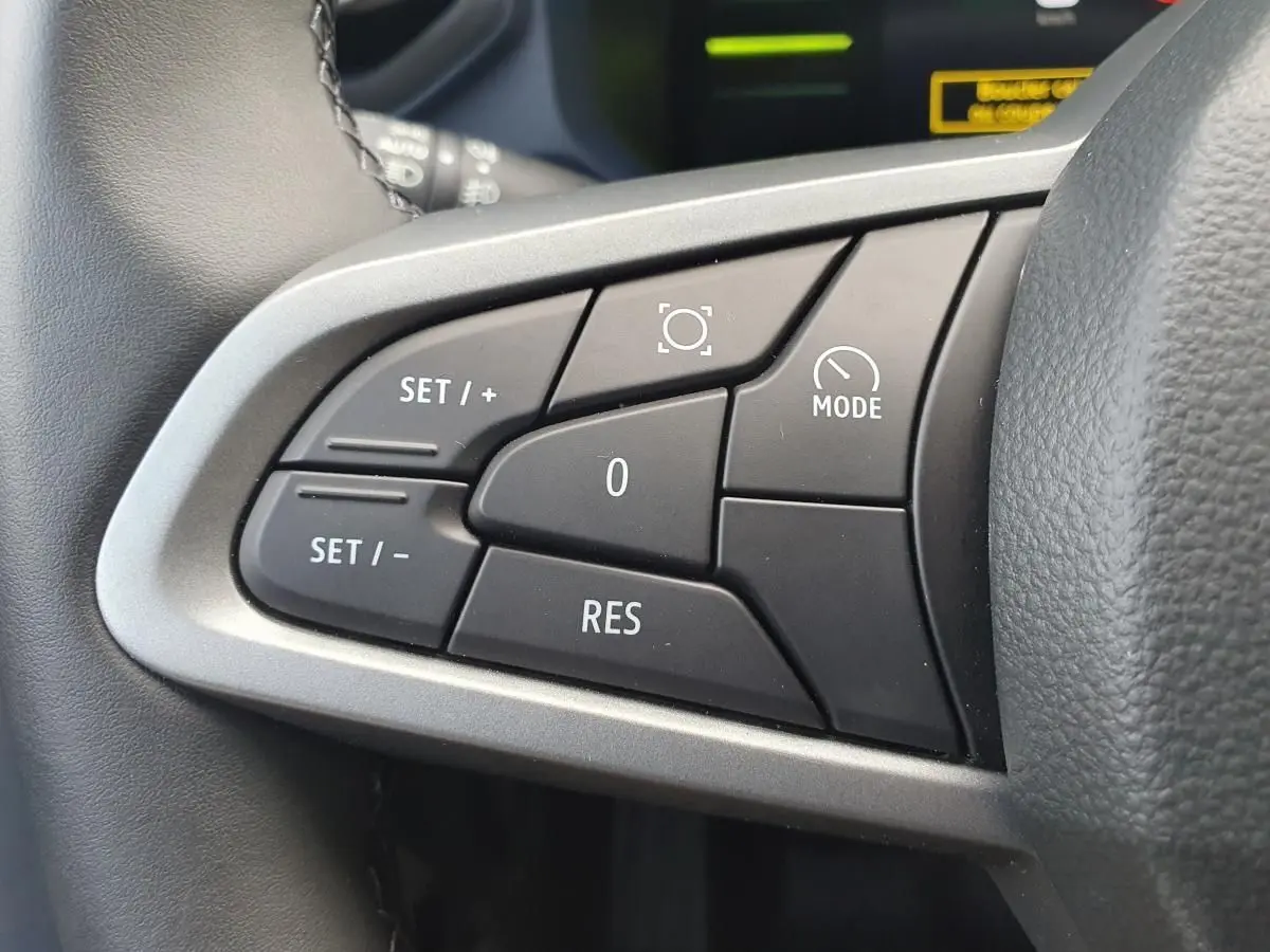 Gros plan sur les commandes de régulateur de vitesse au volant du Dacia Duster 2026, finition gris schiste.