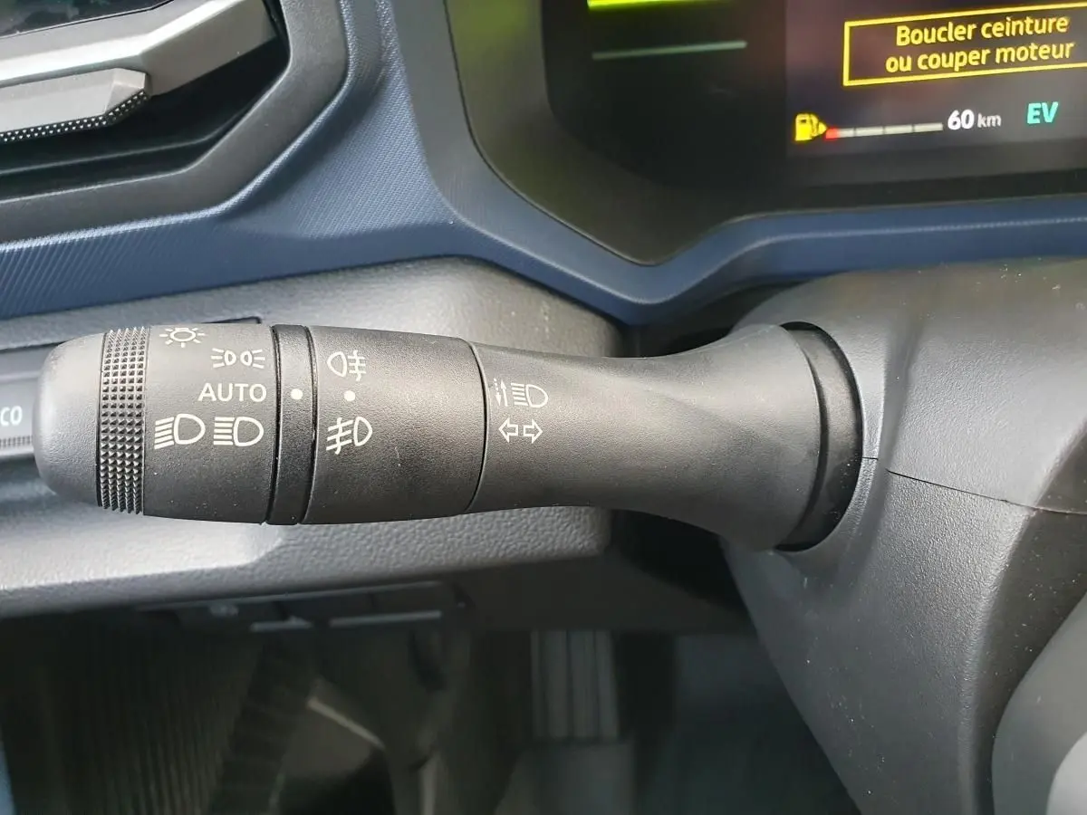 Gros plan sur la commande des feux du tableau de bord du Dacia Duster 1.6 Hybrid 140 gris schiste, affichage digital partiel.