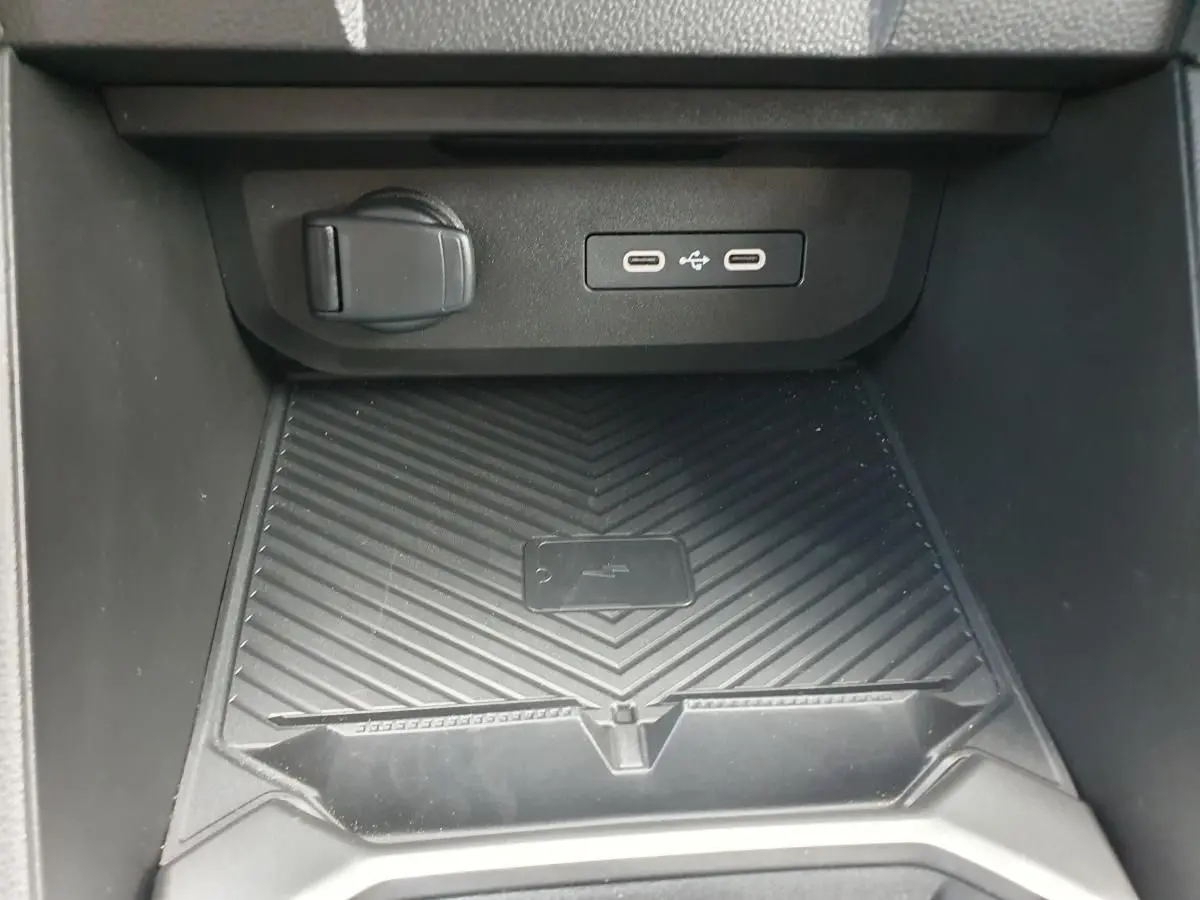 Vue rapprochée de la console centrale du Dacia Duster 2026 montrant la zone de charge sans fil et ports USB.