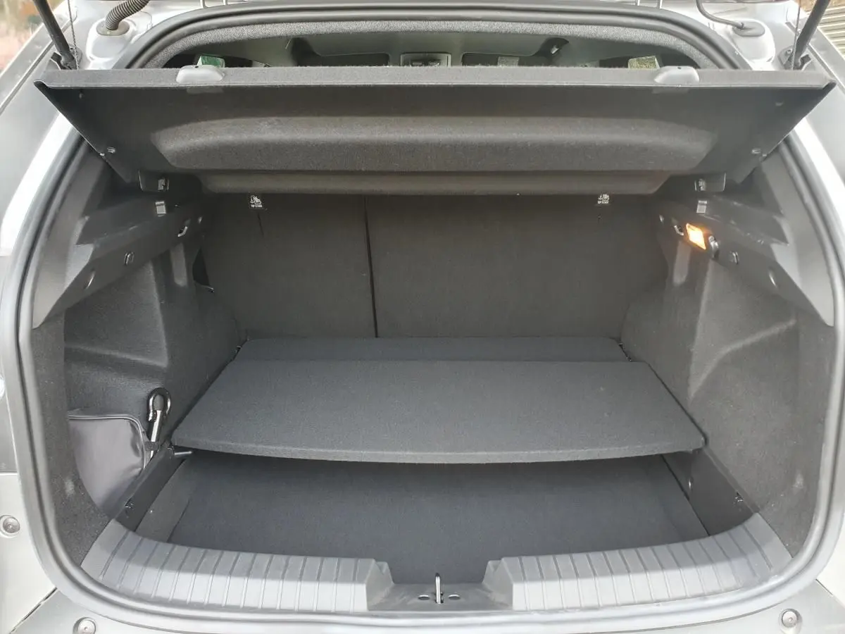 Coffre ouvert vu de l'arrière du Dacia Duster gris schiste, montrant le plancher modulable et l'éclairage intérieur.