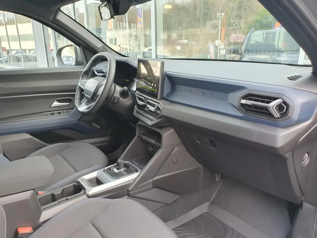 Vue intérieure côté conducteur du Dacia Duster 2026 gris schiste, tableau de bord moderne avec écran tactile central.