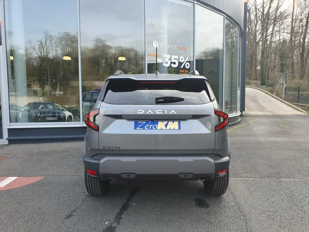 Vue arrière d'un Dacia Duster gris schiste 2026 avec feux LED et logo DACIA bien visibles.