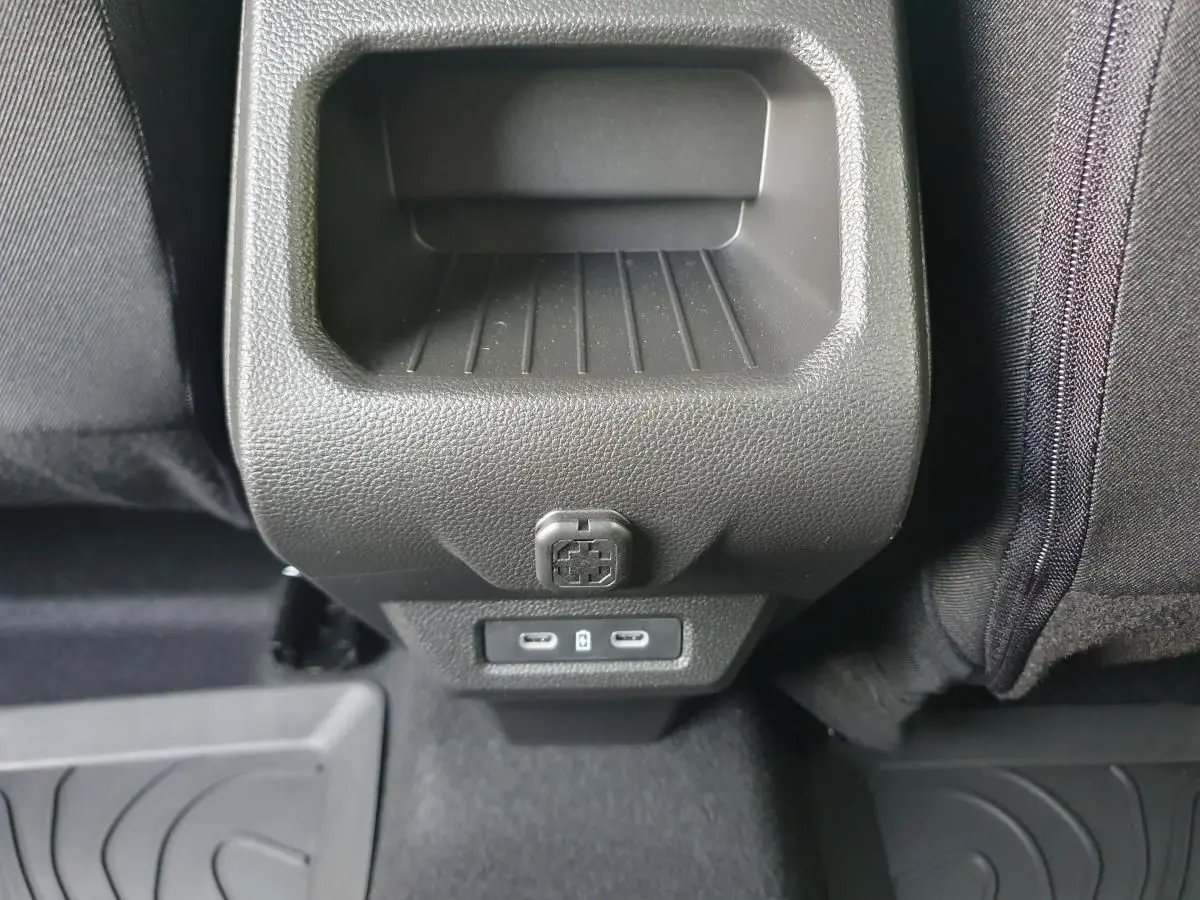 Vue rapprochée de la console arrière noire du Dacia Duster 1.6 Hybrid 140 gris schiste avec prises USB-C et prise 12V.