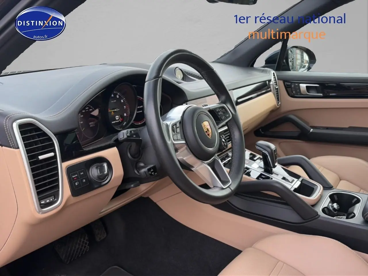 Intérieur beige et noir du Porsche Cayenne 2023, vue côté conducteur sur le volant et la console centrale.