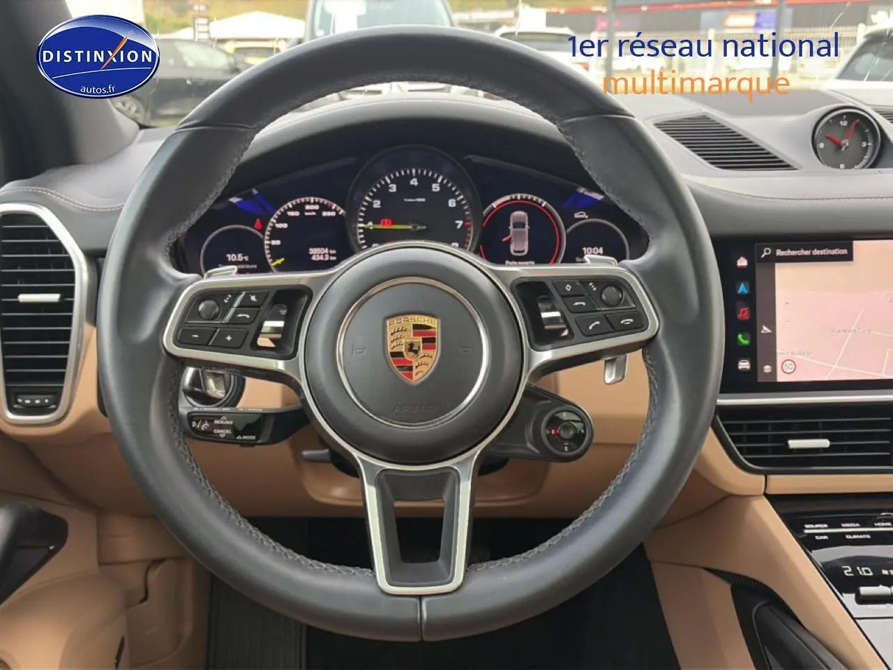 Vue intérieure centrée sur le volant cuir noir et tableau de bord beige du Porsche Cayenne hybride 2023.
