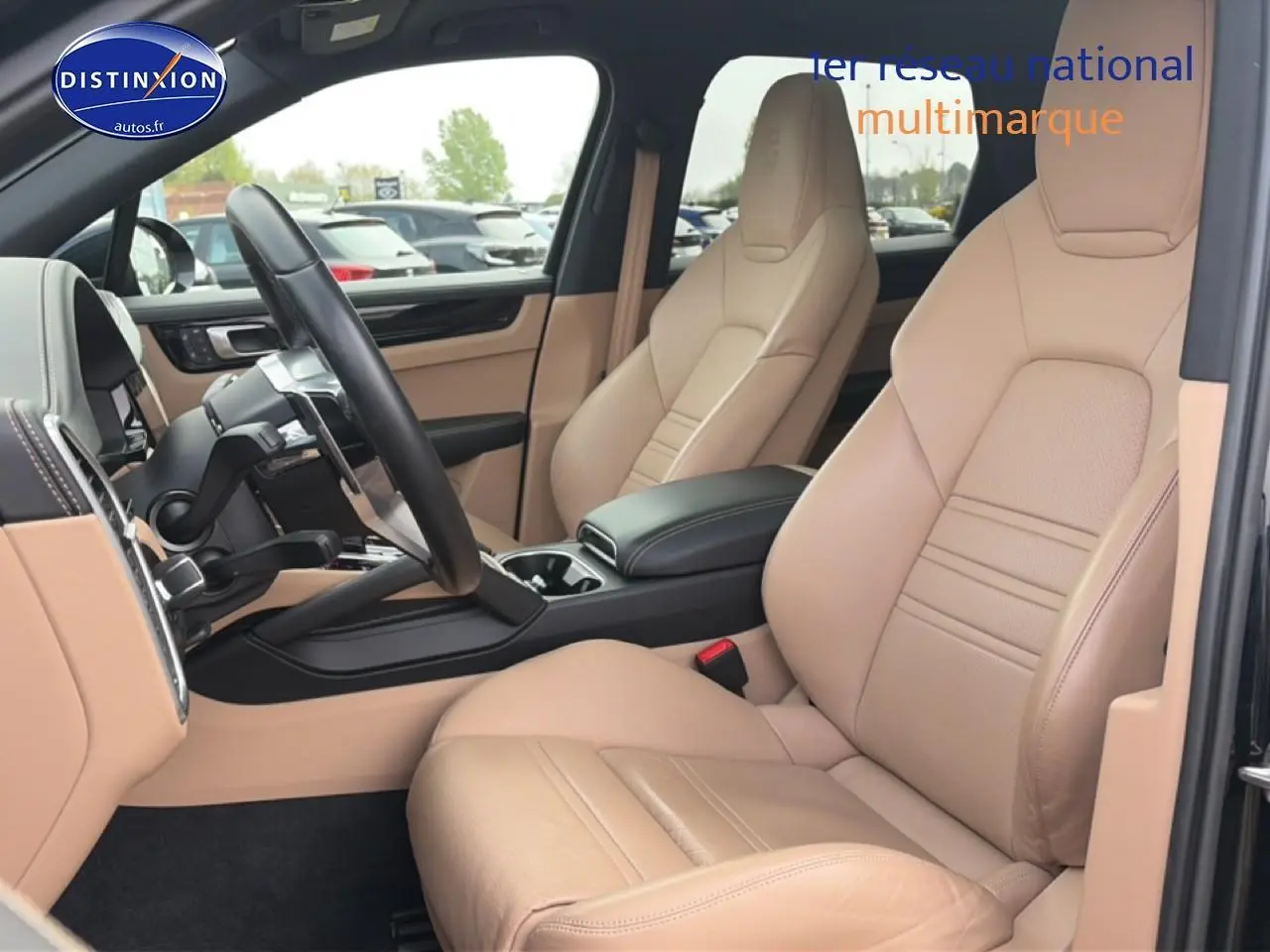 Vue intérieure côté conducteur de la Porsche Cayenne 2023 avec sièges en cuir beige et volant multifonction noir.